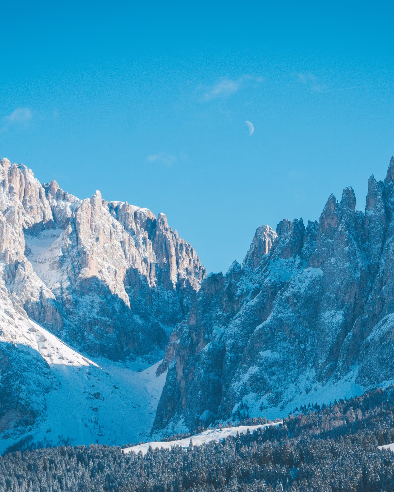 Snow-covered rocky peaks rise beneath a clear blue winter sky.