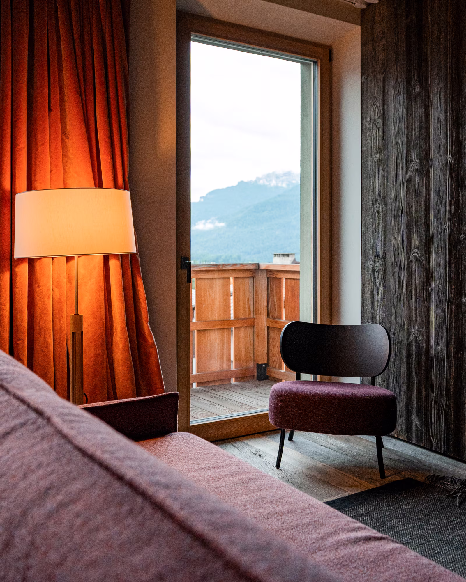 Wood-lined guest room opening onto a mountain-facing terrace.