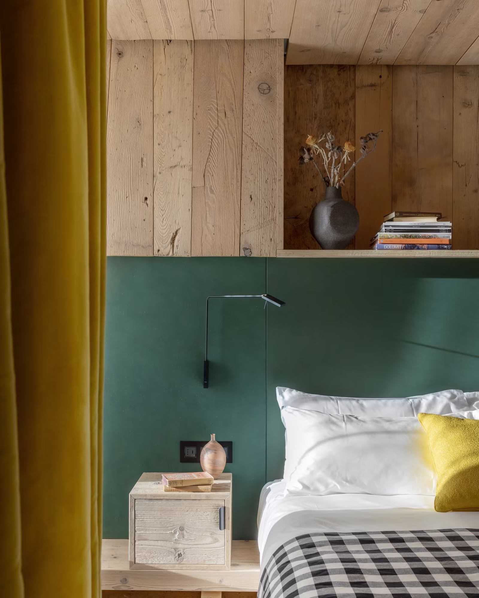 Guest room with pale timber walls and a green headboard.